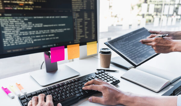 Writing codes and typing data code technology, Programmer cooperating working on web site project in a software developing on desktop computer at company, Programming with HTML, PHP and javascript.